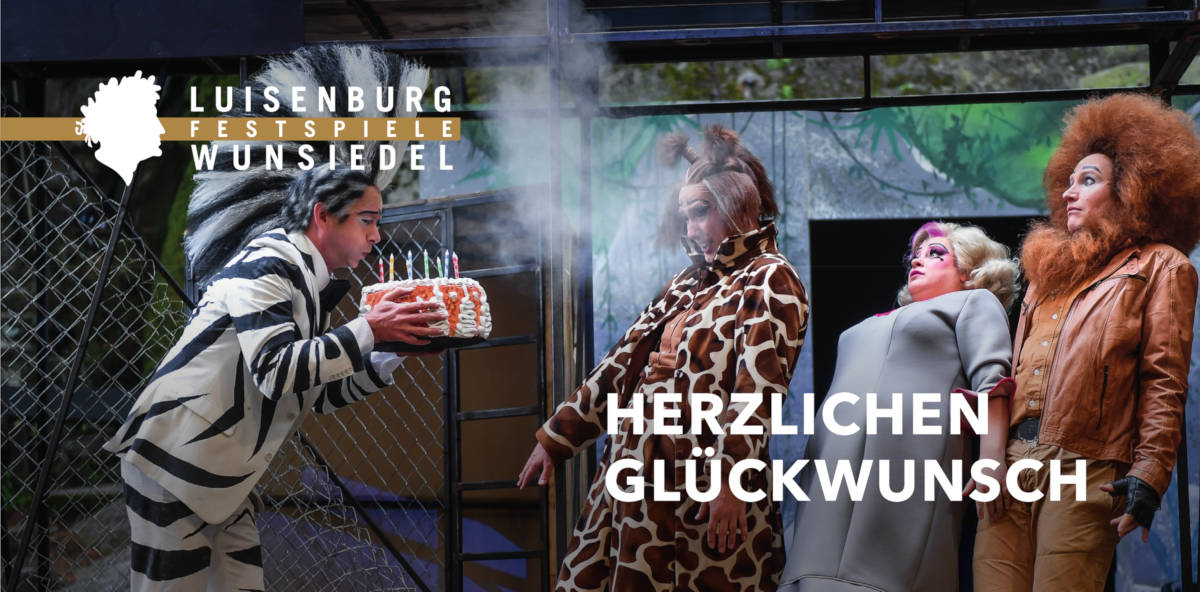 Personen mit bunten Tierkostümen pusten Kerzen von einer Torte