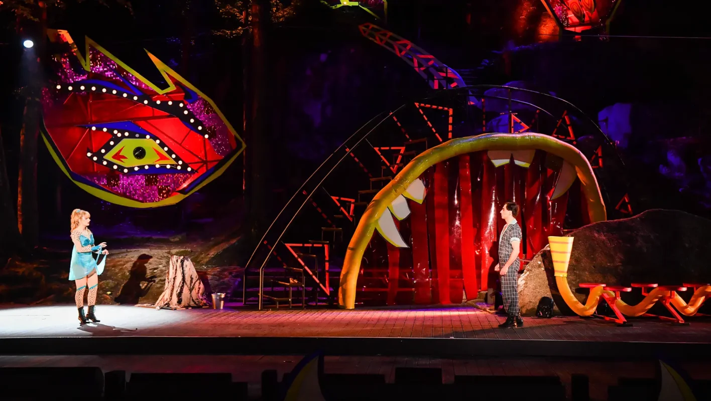 Zwei Darsteller auf einer farbig üppigen Bühne