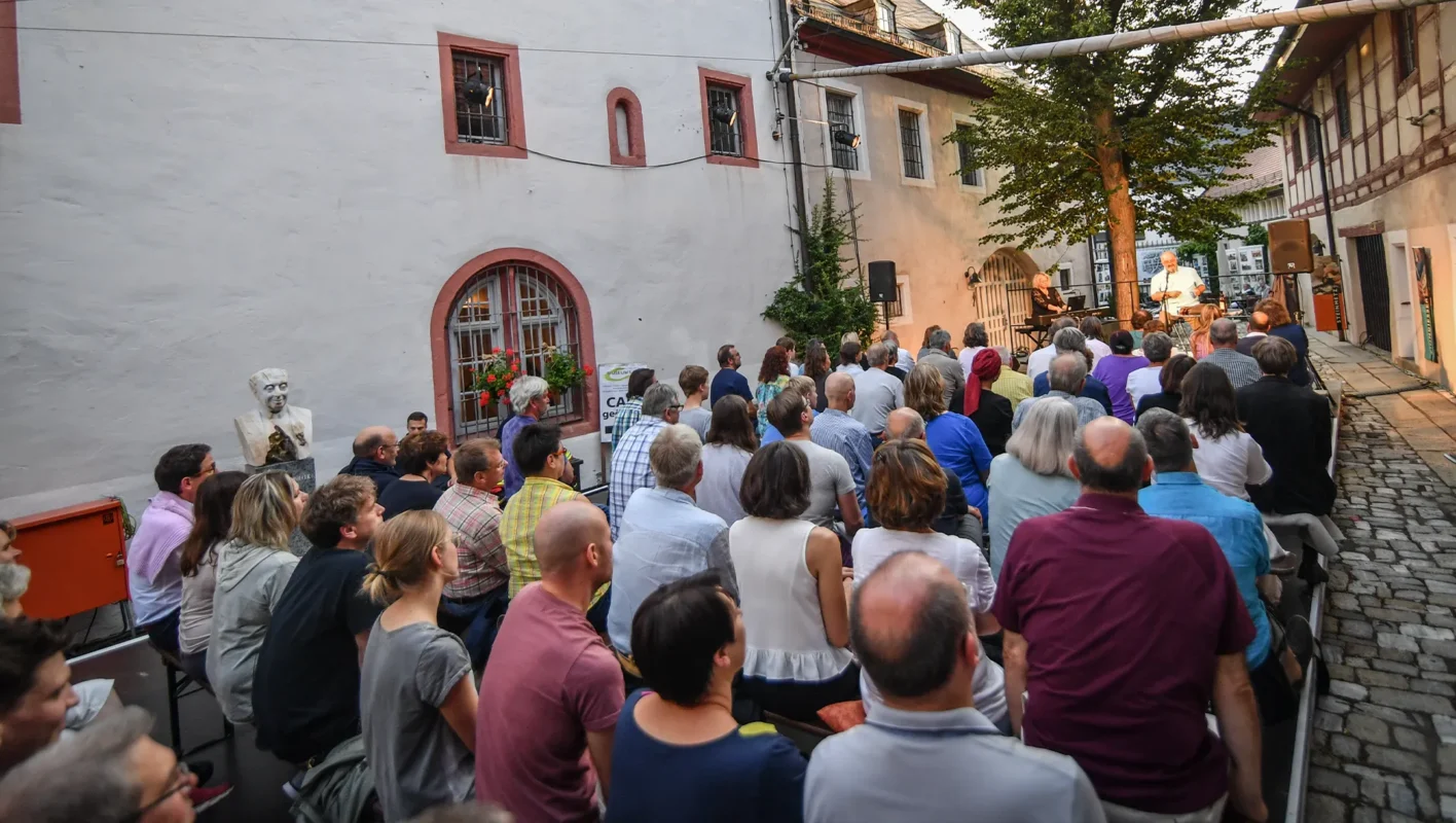 Gruppe von sitzenden Menschen in einer engen Gasse