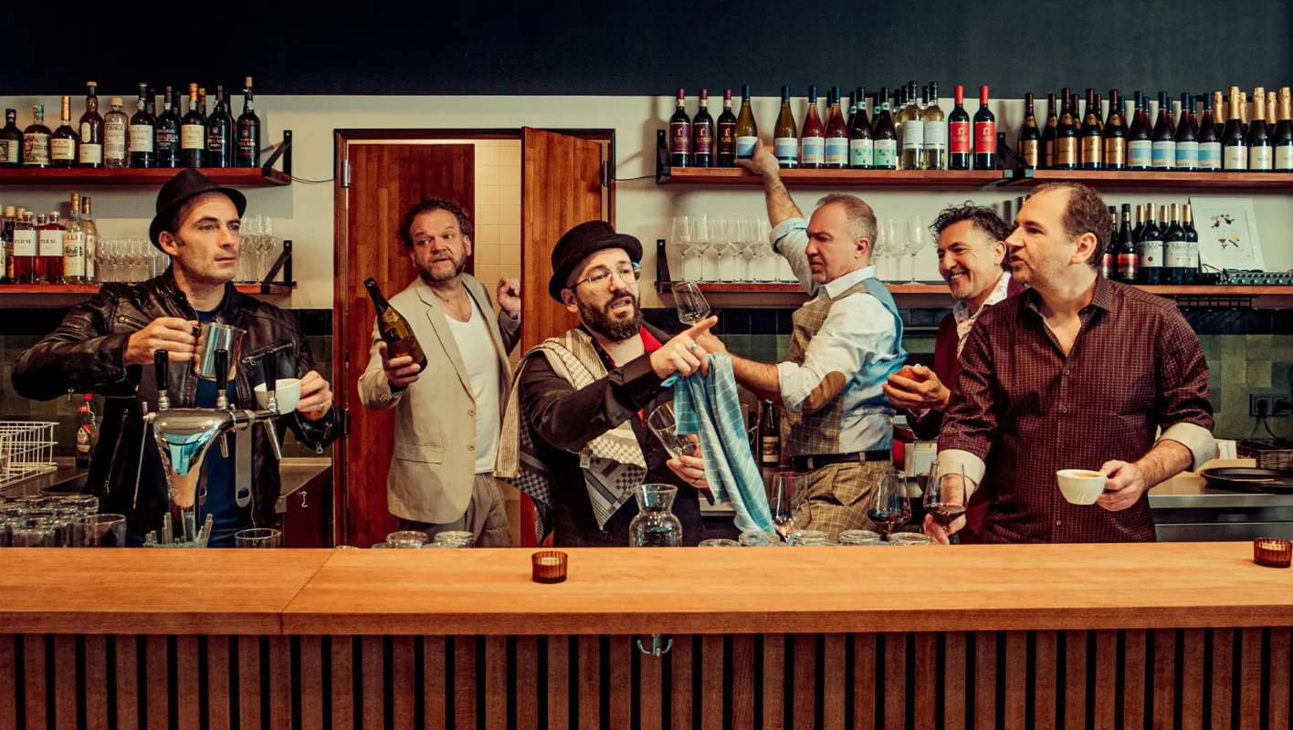 6 Männer hantieren mit Gläsern und Flaschen hinter einer Theke