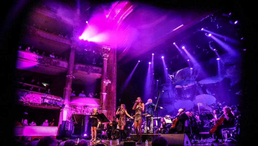 Farbig erleuchtete Bühne mit Sängerinnen und Orchester